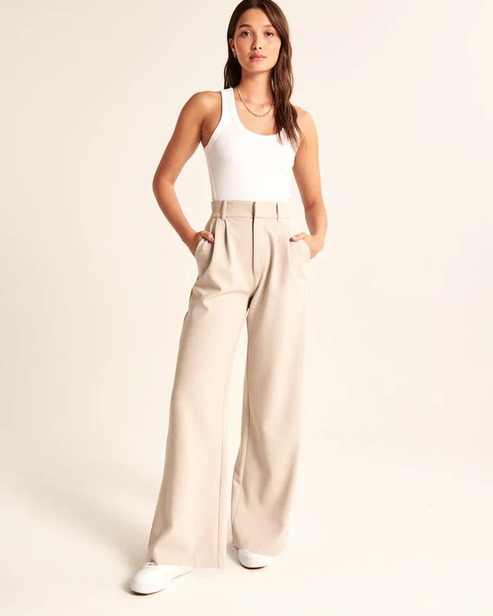 Model wearing women's beige wide-leg tailored trousers, high-waist, elegant style for both formal and casual occasions.