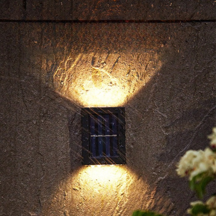 Outdoor waterproof solar wall light with motion sensor, black finish, mounted on a stone wall, illuminating a garden path.