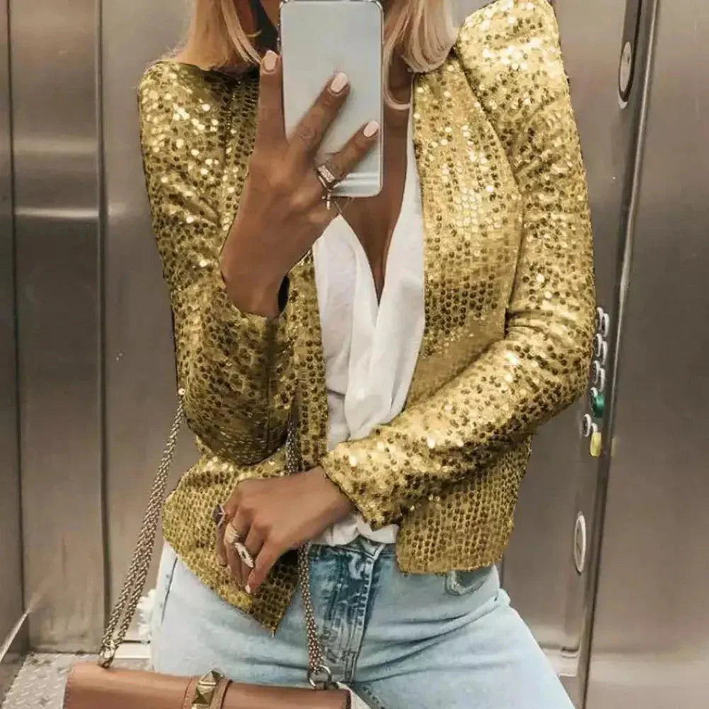 A woman wearing a black sequin cropped blazer, styled as formal evening wear, paired with a marine blue dress shirt. The blazer features a polished shoulder design, long sleeves, and a fitted waist, with the overall look completed by the woman's stylish eyewear.