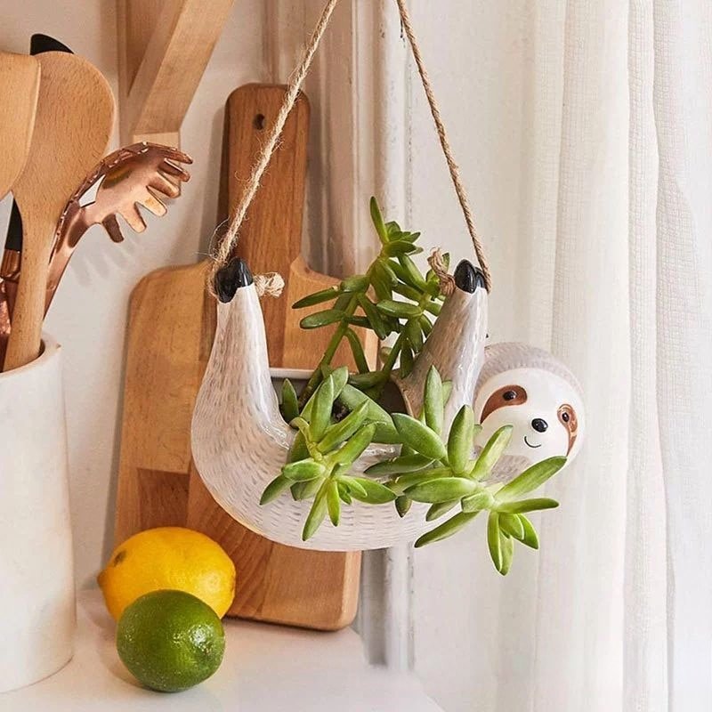 Ceramic sloth hanging flowerpot with hemp rope; whimsical design in blue, grey, or khaki, perfect for home decor.