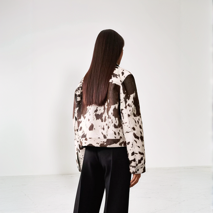 Cow print structured jacket, front view, single-breasted design, black and white pattern, women's fashion statement piece.
