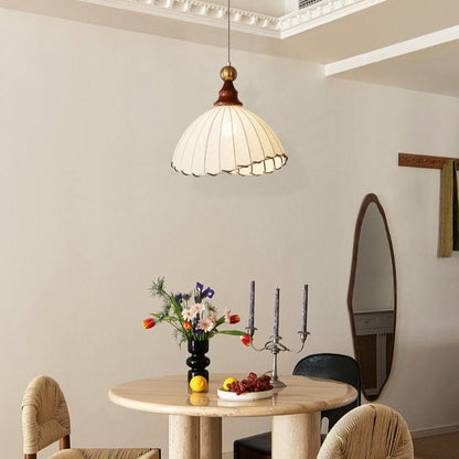 Elegant pendant light with pleated fabric shade, gold-finished top, and wood accent; perfect for modern interiors.
