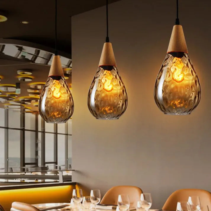 "Elegant teardrop glass pendant light with wood accents, available in clear, golden, smoky gray, perfect for any home decor."