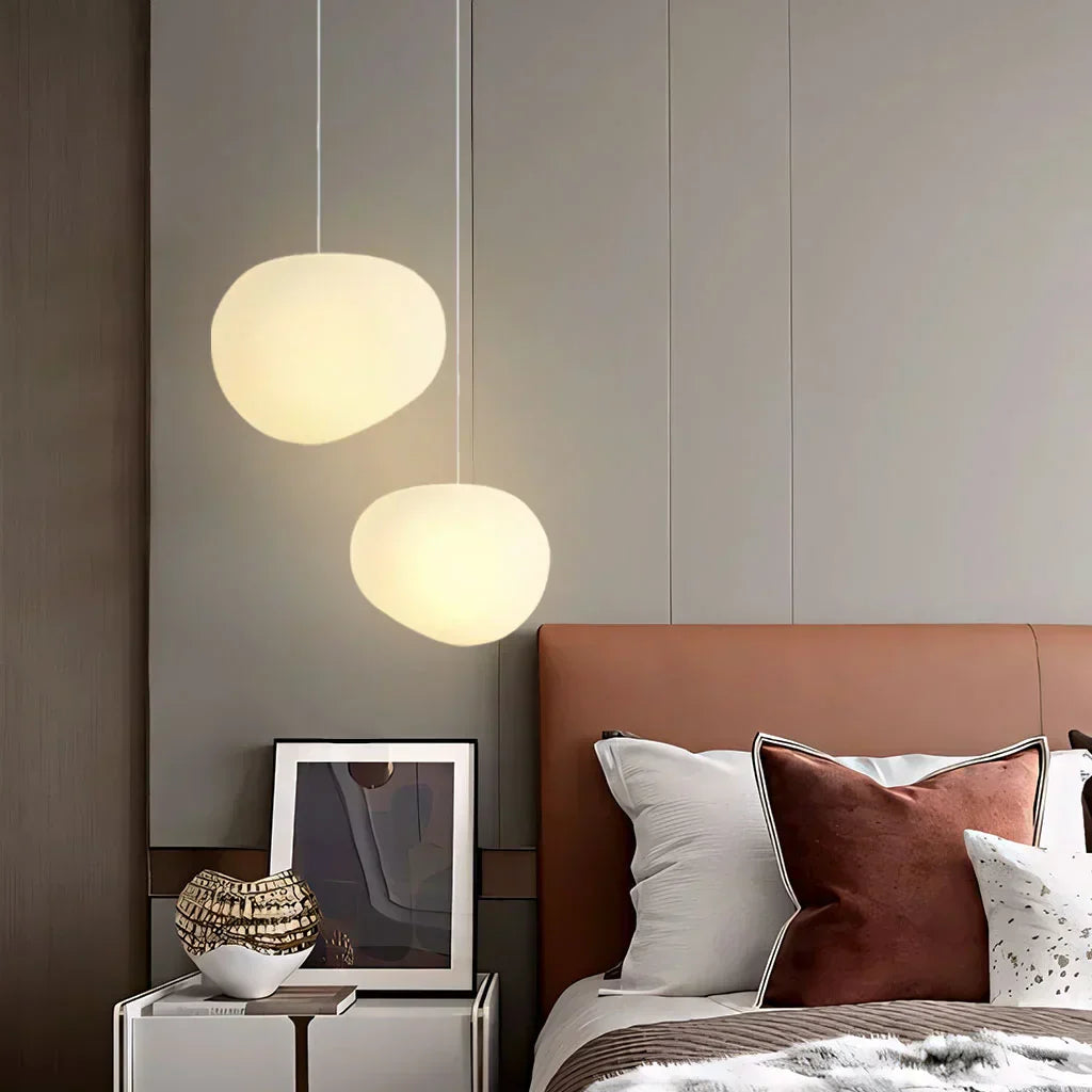 Elegant white pebble pendant light; minimal design, frosted glass, metal accents, soft glow for modern interiors.