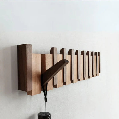 "Elegant wooden coat rack with piano key design, featuring multiple hooks for organizing coats and accessories."