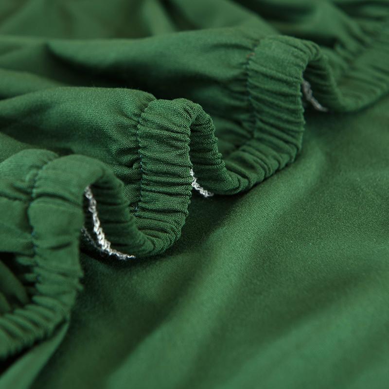 "Emerald green sofa cover on a couch, showcasing its stretchy and durable fabric, perfect for protection and style."