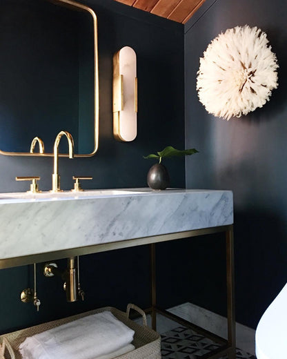 "Modern elongated alabaster wall lamp with metal and brass accents, emits warm glow, suitable for chic interior decor."
