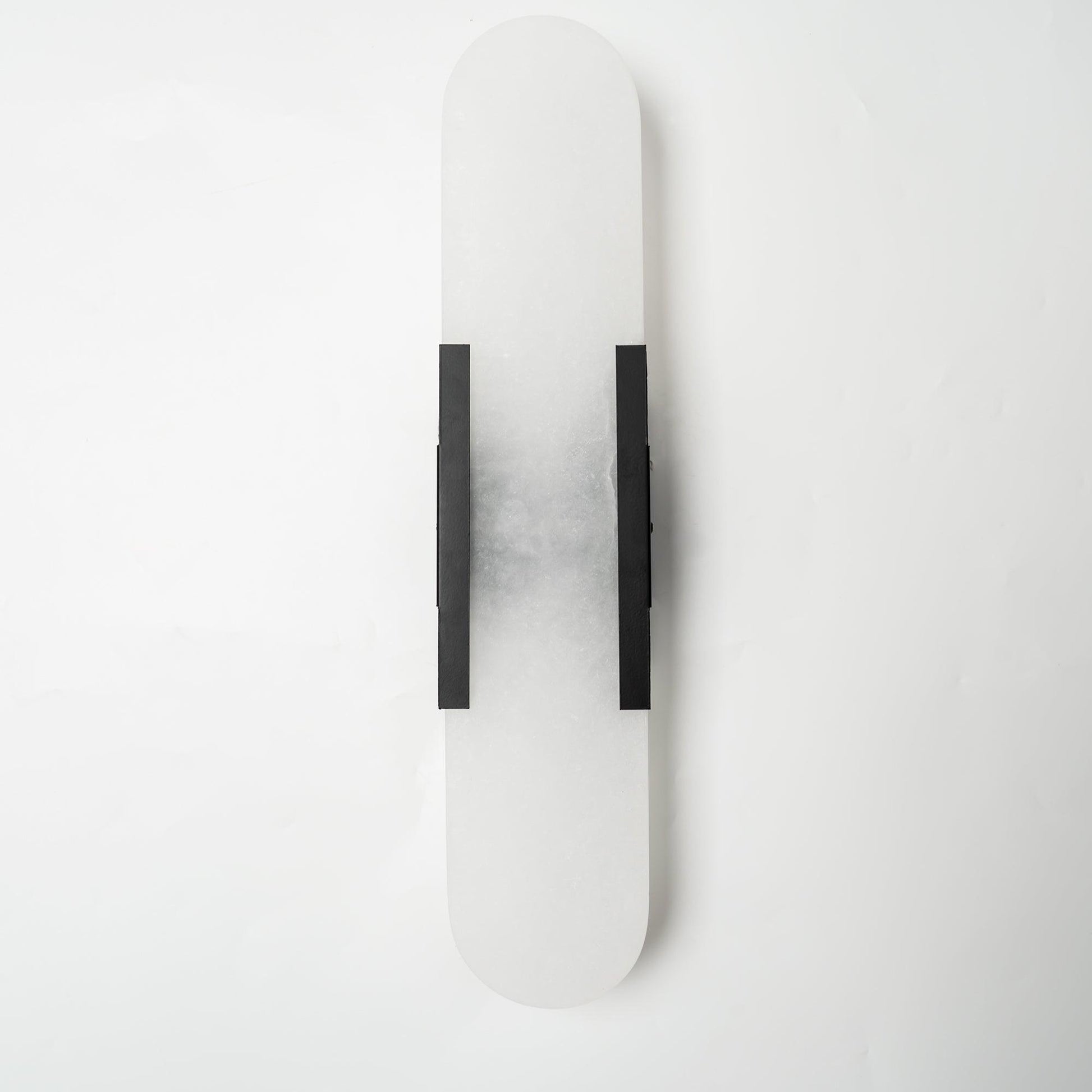 "Modern elongated alabaster wall lamp with metal and brass accents, emits warm glow, suitable for chic interior decor."