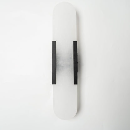 "Modern elongated alabaster wall lamp with metal and brass accents, emits warm glow, suitable for chic interior decor."