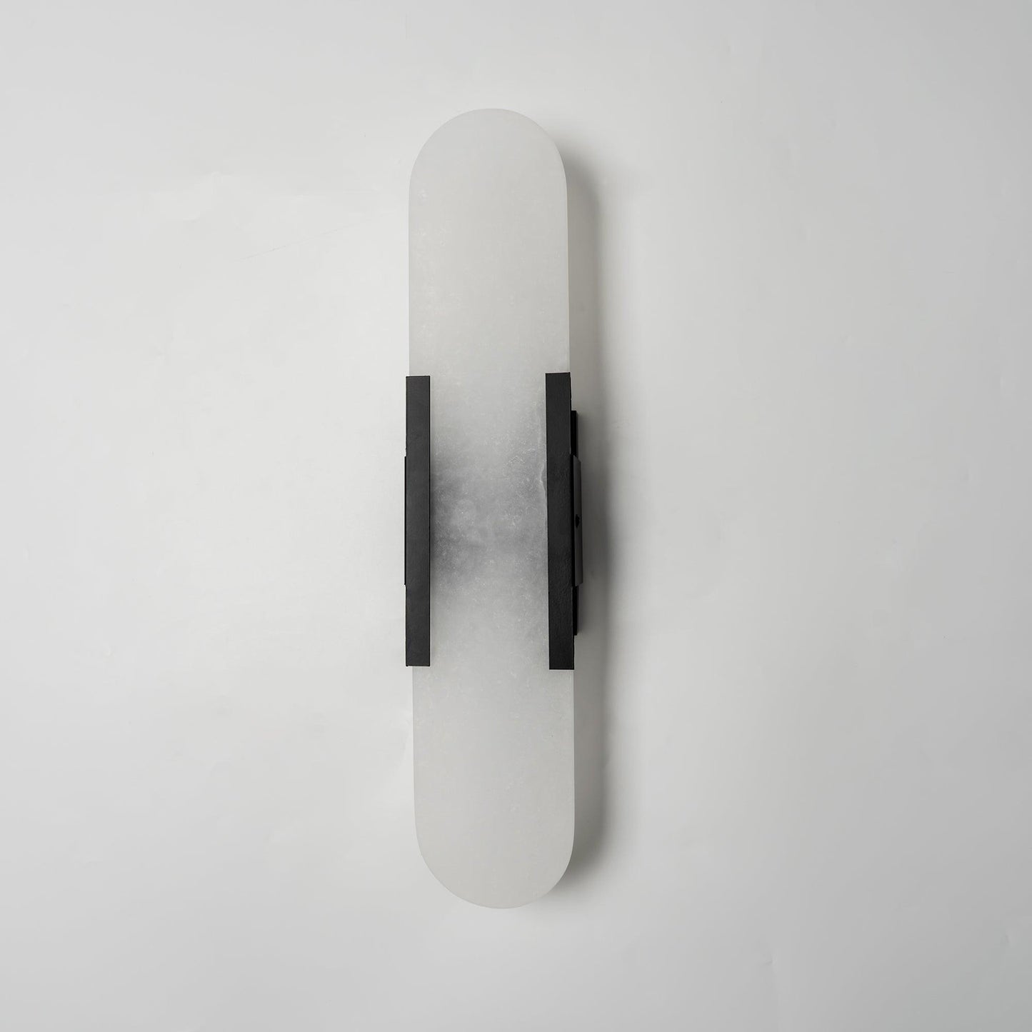"Modern elongated alabaster wall lamp with metal and brass accents, emits warm glow, suitable for chic interior decor."