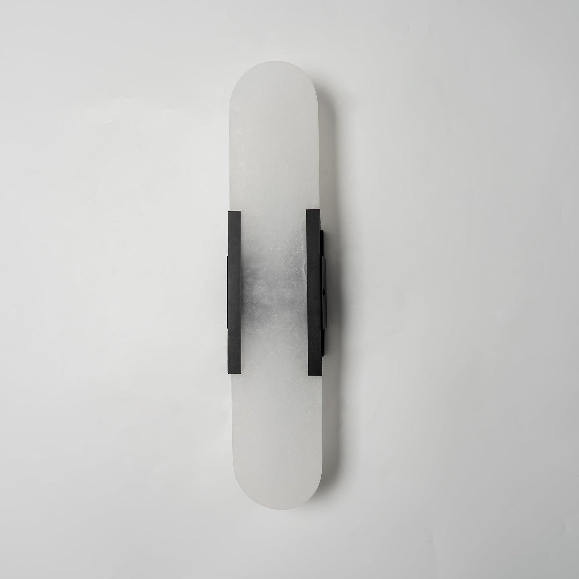 "Modern elongated alabaster wall lamp with metal and brass accents, emits warm glow, suitable for chic interior decor."