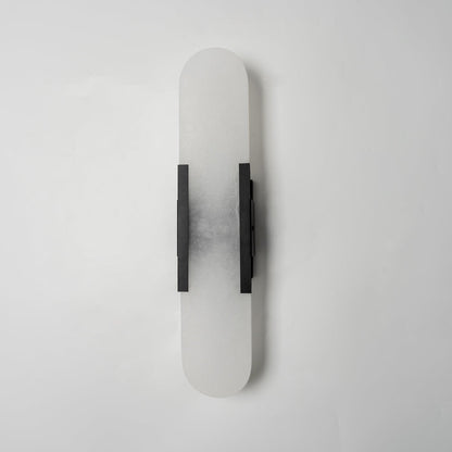 "Modern elongated alabaster wall lamp with metal and brass accents, emits warm glow, suitable for chic interior decor."