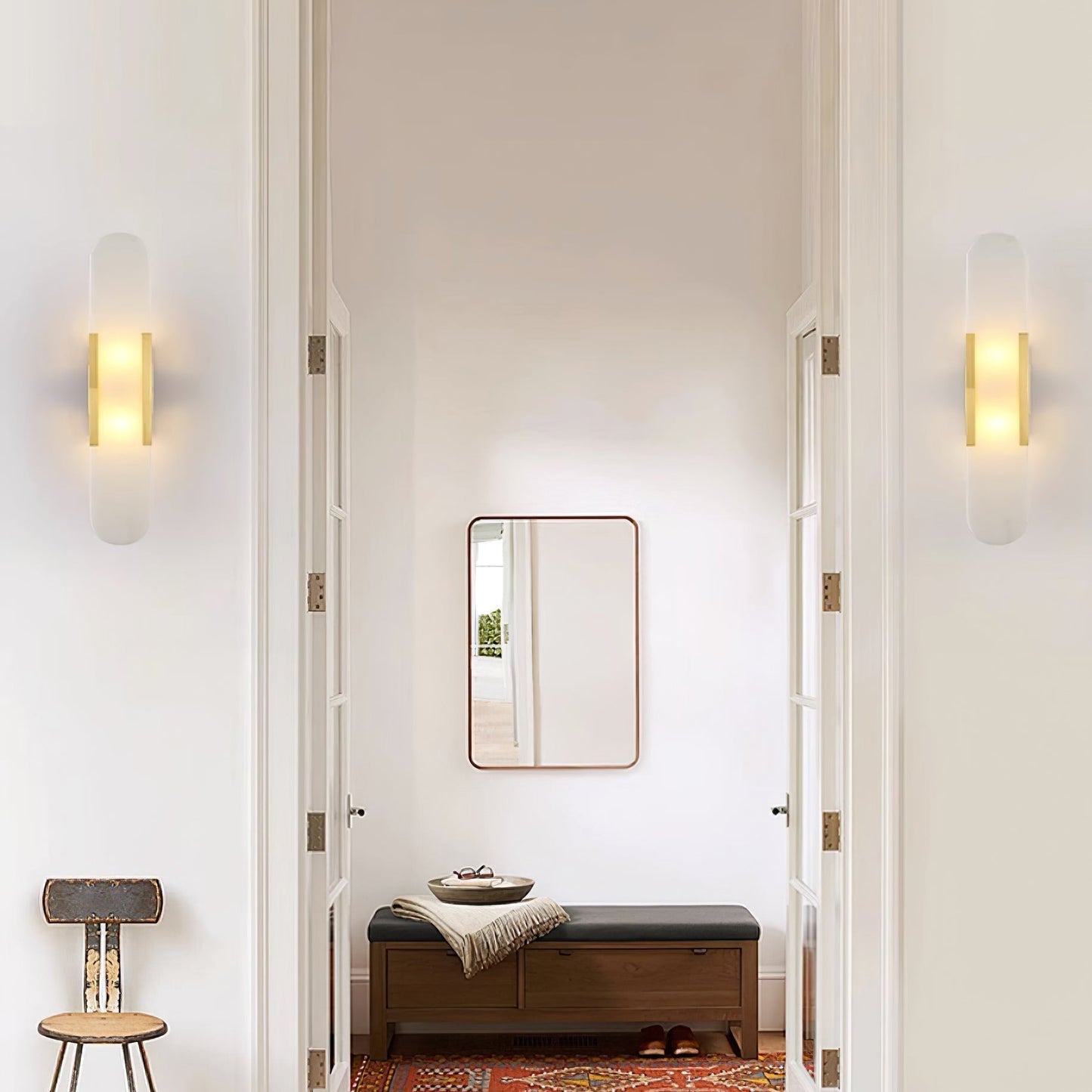 "Modern elongated alabaster wall lamp with metal and brass accents, emits warm glow, suitable for chic interior decor."