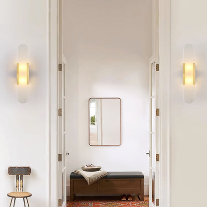"Modern elongated alabaster wall lamp with metal and brass accents, emits warm glow, suitable for chic interior decor."
