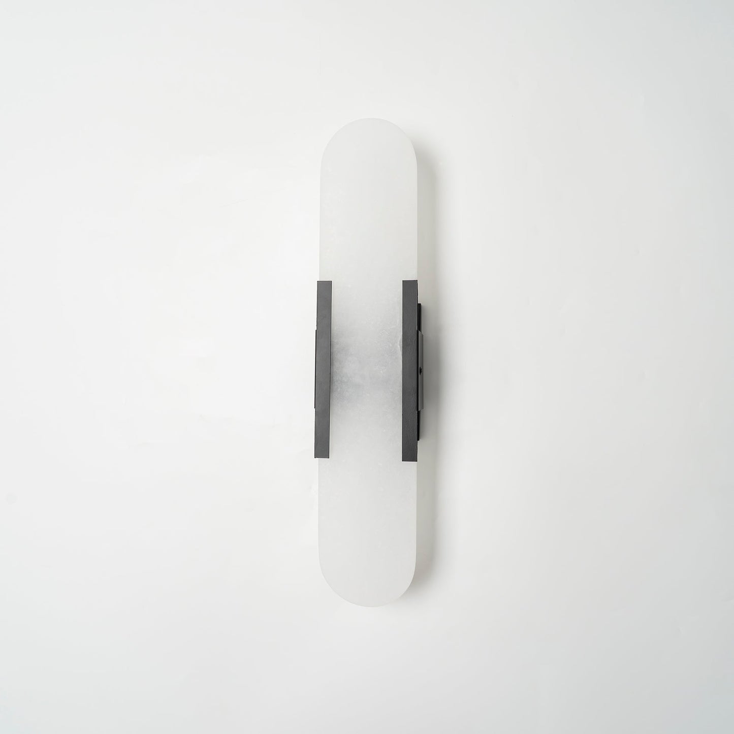 "Modern elongated alabaster wall lamp with metal and brass accents, emits warm glow, suitable for chic interior decor."