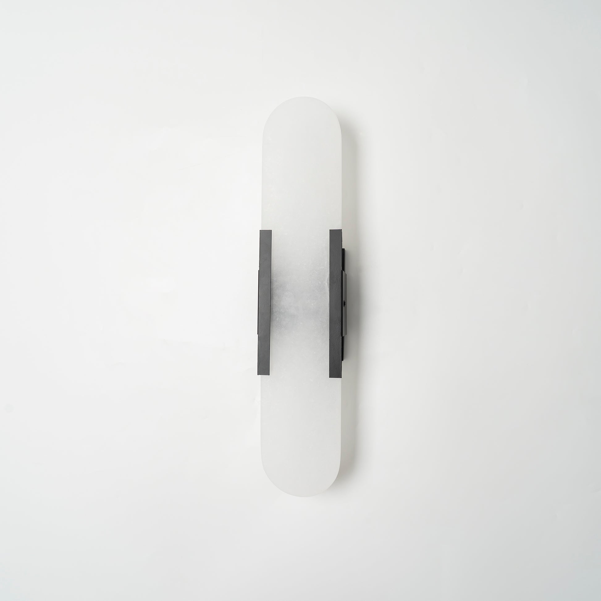 "Modern elongated alabaster wall lamp with metal and brass accents, emits warm glow, suitable for chic interior decor."