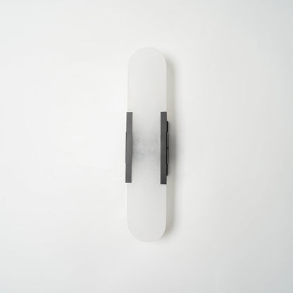 "Modern elongated alabaster wall lamp with metal and brass accents, emits warm glow, suitable for chic interior decor."