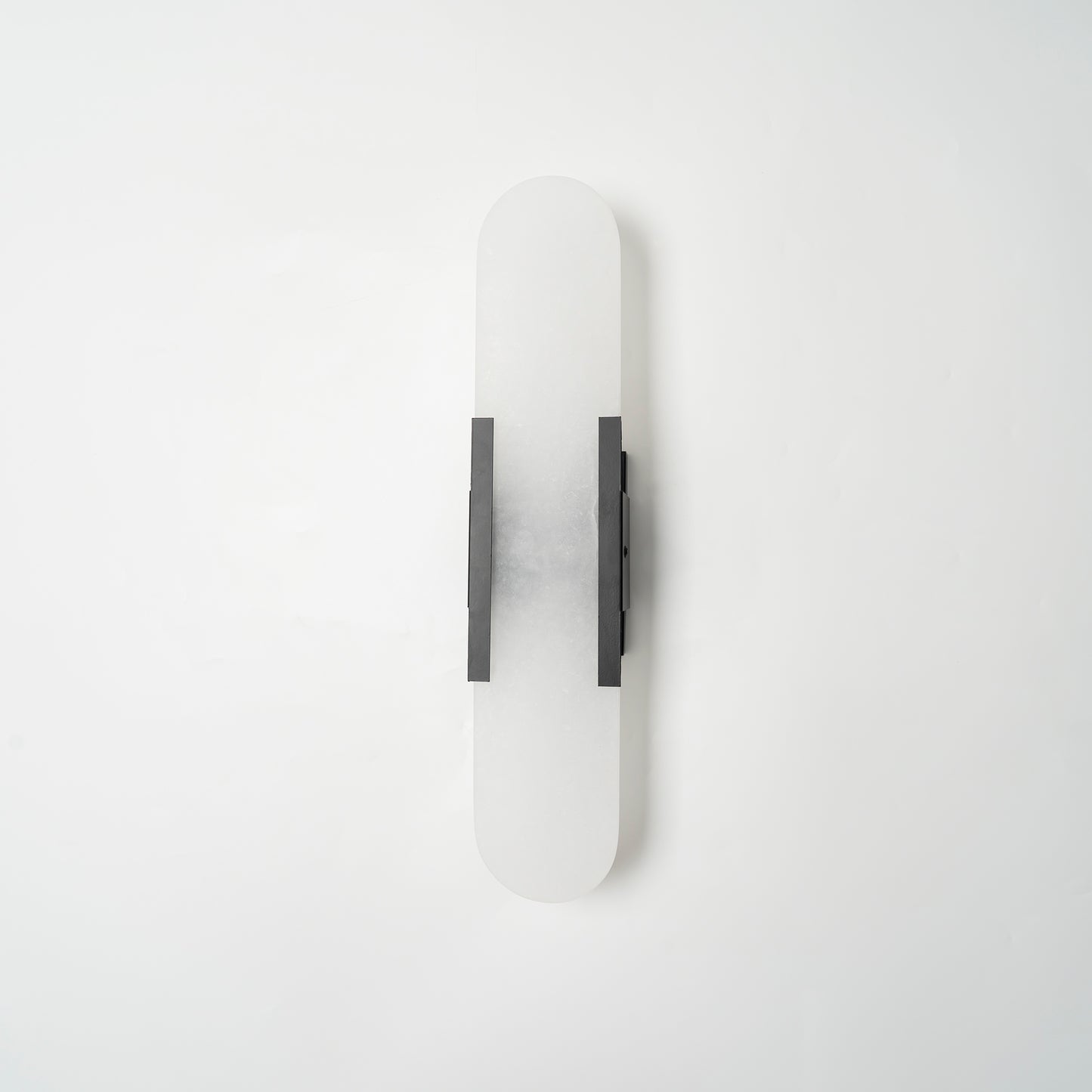 "Modern elongated alabaster wall lamp with metal and brass accents, emits warm glow, suitable for chic interior decor."