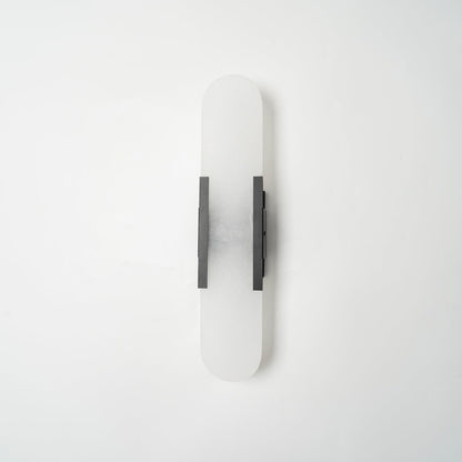 "Modern elongated alabaster wall lamp with metal and brass accents, emits warm glow, suitable for chic interior decor."