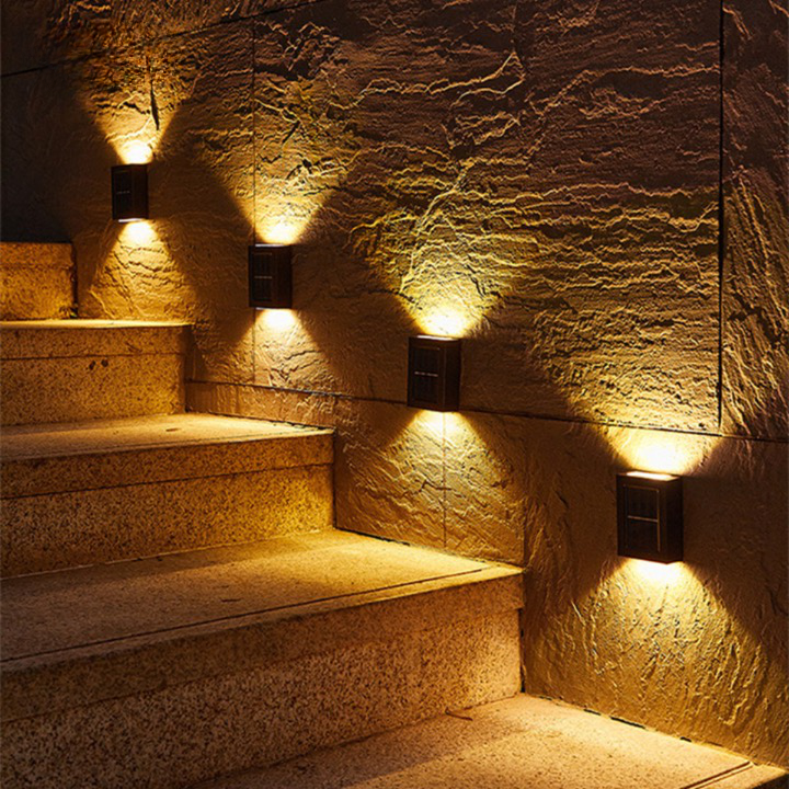 Outdoor waterproof solar wall light with motion sensor, black finish, mounted on a stone wall, illuminating a garden path.