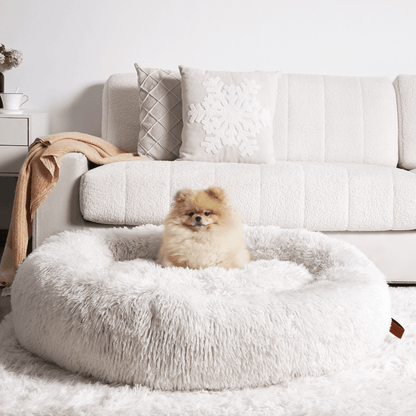 "Plush apricot donut dog bed, anxiety-relieving, round with raised rim, faux fur, for dogs to curl up comfortably."