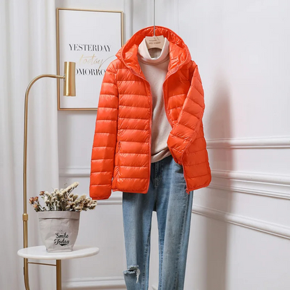 "Women's ultralight foldable puffer jacket with hood, chic design, lightweight, perfect for travel and cold weather."